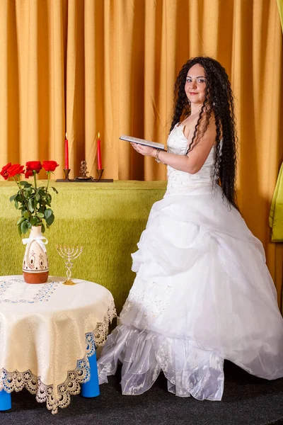 一位身着白色婚纱婚纱的犹太新娘在婚礼前在房间里朗诵着提格琳的祷文 垂直照片 — 图库照片