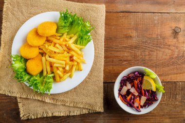 Tavuk nugget ile patates kızartması, Cole 'un yanında, ahşap bir masada peçetenin üzerinde yavaşça. Yatay fotoğraf
