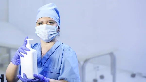 Eldivenli ve maskeli bir doktor elinde antiseptik tutuyor. Yatay fotoğraf