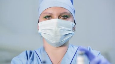 Aşıyı ve şırıngayı kadın doktorların ellerinde keskin bir bulanıklıkla yüzleştir..