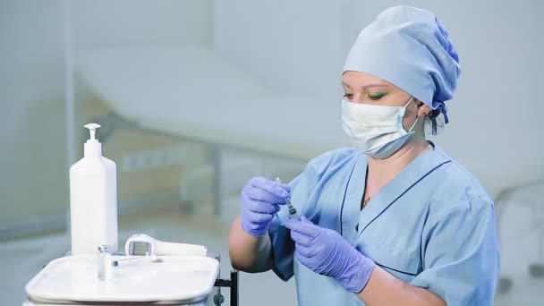 A female doctor in a medical mask is filling a syringe with a vaccine — Stock Video