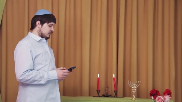 Before the chuppah ceremony, a Jewish groom in the synagogue hall dials an SMS by phone — Stock Video