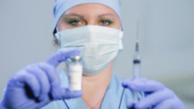 Aşıyı ve şırıngayı kadın doktorların ellerinde keskin bir bulanıklıkla yüzleştir.