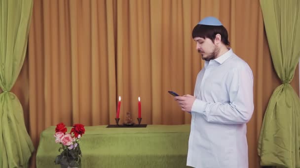 Antes da cerimônia do chuppah, um noivo judeu no salão da sinagoga marca um SMS por telefone. — Vídeo de Stock