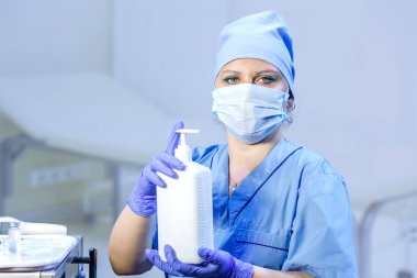 Eldivenli ve maskeli bir doktor elinde antiseptik tutuyor. Yatay fotoğraf