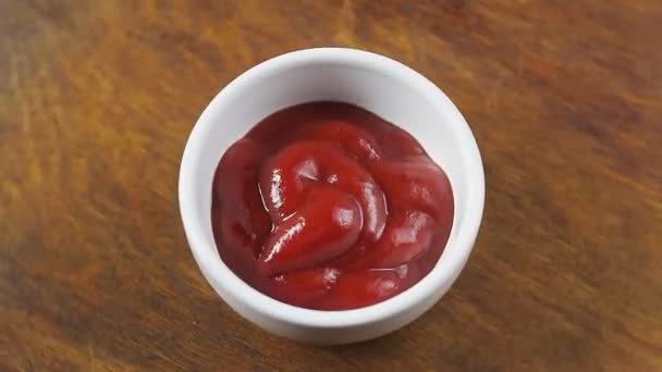 El ketchup de tomate en un bote de salsa blanca sobre un soporte de madera gira en círculo — Vídeos de Stock