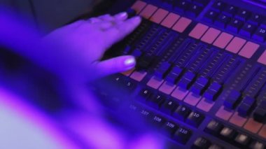 Aydınlatma odasındaki uzaktan kumandalı kadın aydınlatma aletlerini kontrol eder.