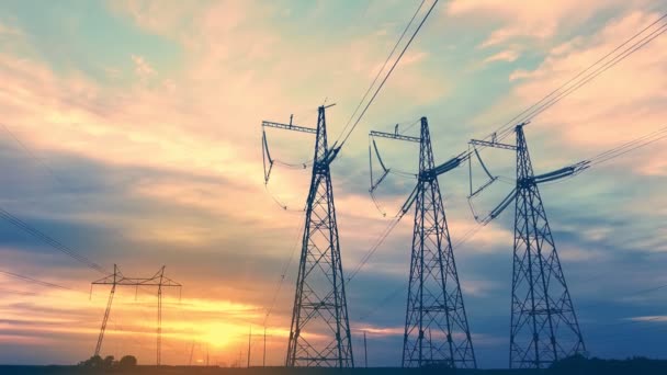 Líneas eléctricas de alto voltaje al atardecer contra el telón de fondo del sol poniente en un vídeo aéreo de área abierta — Vídeos de Stock