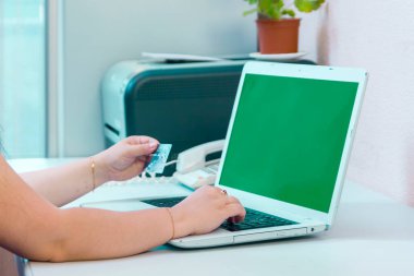 Çevrimiçi yeşil ekran alırken bir kadının elinde banka kartı var. Yatay fotoğraf