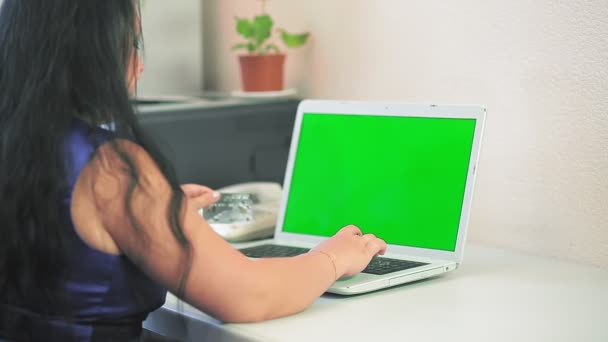 ブルネットの女性は緑の画面の銀行カードでオンラインで支払うことによってインターネット上で購入を行います — ストック動画