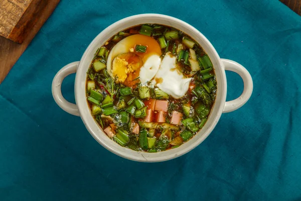 Okroshka kvass ile süslenmiş bir tencerede, yumurta ve ekşi kremayla süslenmiş..