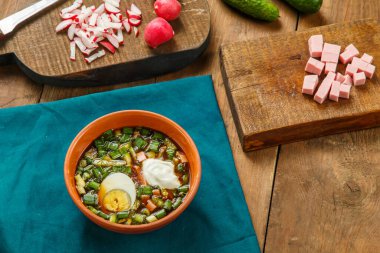 Okroshka kil tabakta masanın üstünde, masada sebzelerin yanında. Yatay fotoğraf