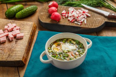 Sebzelerin yanındaki mavi peçetenin üzerinde kvass tablasıyla Okroshka. Yatay fotoğraf