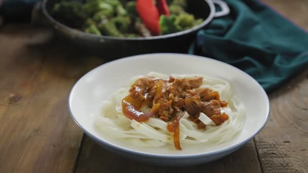 Eine Frauenhand legt Gemüse auf Udon mit Fleisch in Yakiniku-Sauce — Stockvideo