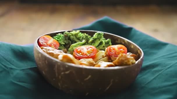 Udon avec viande et légumes en sauce yakiniku dans une assiette de coquilles de noix de coco sur une serviette bleue tourne en cercle. — Video