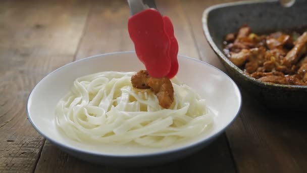 Zange legt Fleisch in Yakiniku-Sauce in einen Teller mit Udon. — Stockvideo