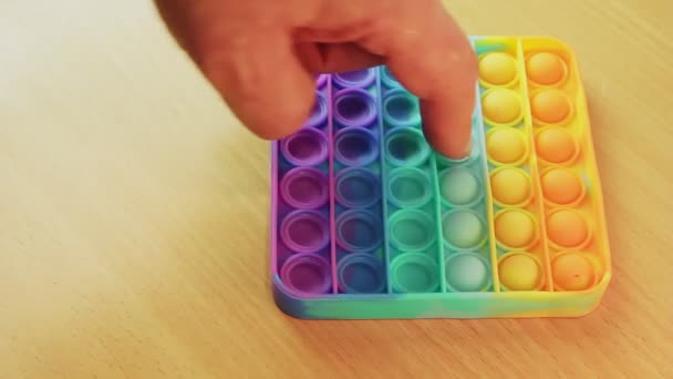 Há um pop colorido anti-stress na mesa, as pessoas dedos estão pressionando sobre ele. — Vídeo de Stock