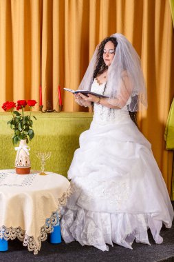 Beyaz elbiseli, yüzü çiçekli bir masada örtülü bir Yahudi gelin Chupa seremonisinden önce Tethe okur. Dikey fotoğraf
