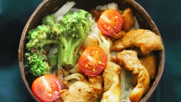 Udon mit Fleisch und Gemüse in Yakiniku-Sauce in einem Teller mit Kokosnussschalen auf einer blauen Serviette dreht sich im Kreis — Stockvideo
