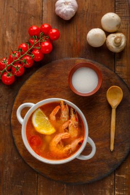 Tom tatlı patates çorbası, karides ve hindistan cevizi sütü ile hindistan cevizi sütünün yanında yuvarlak bir tahtanın üzerinde. Dikey fotoğraf