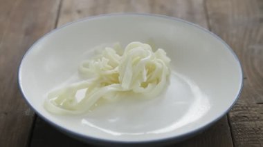Erişteleri tabağa koymak için maşa kullanın..