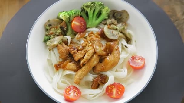 Bovenaanzicht Udon met vlees en groenten in yakiniku saus in een bord draaiend in een cirkel. — Stockvideo