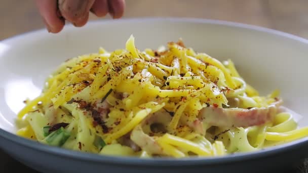 Egy nő kézzel megszórja a carbonara tésztát egy tányérba. — Stock videók