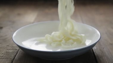 Erişteleri tabağa koymak için maşa kullanın.