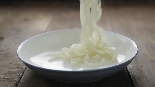 Utilice pinzas para colocar fideos udon en el plato — Vídeo de stock