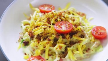 Kremalı Carbonara soslu spagetti tabakları ve daire şeklinde dönen kiraz domatesleri.