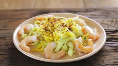 Bir kadın makarnayı kremalı soslu ve peynirli karideslerle süslüyor.