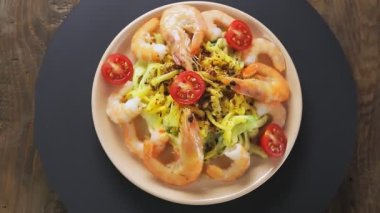 Kremalı soslu makarna, siyah bir stantta tabakta karidesler daire şeklinde döner.