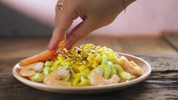 Ένα γυναικείο χέρι διακοσμεί ζυμαρικά με βασιλικές γαρίδες σε κρεμώδη σάλτσα και τυρί σε πιάτο. — Αρχείο Βίντεο