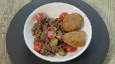 Patates ve kiraz domatesli rosto ve siyah bir büfede balık kekleri daire şeklinde dönüyor.