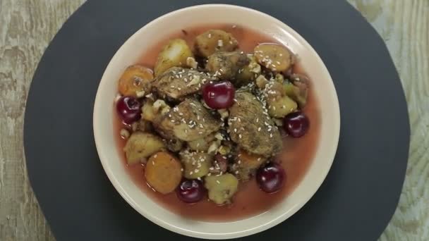Jewish roast dish with chicken in cherry sauce on a black background rotates in a circle top view — Stock Video