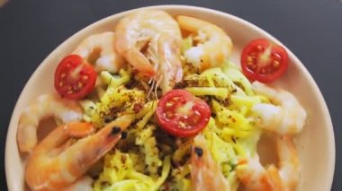 Kremalı soslu spagetti tabakları karides ve çember şeklinde dönen kiraz domatesleri.