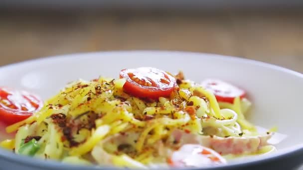 Die Pasta in einer cremigen Carbonara-Sauce und die Gewürze in einem Teller drehen sich im Kreis — Stockvideo