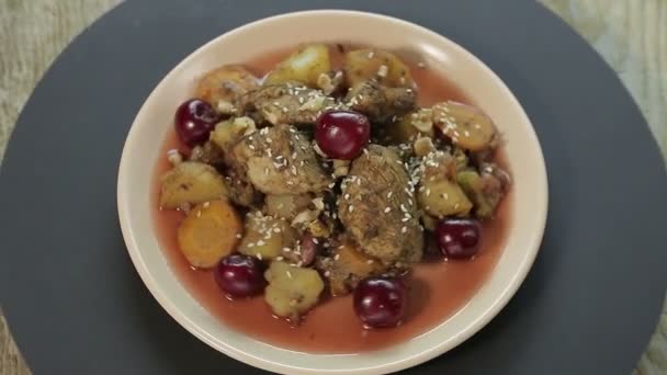 Plato asado judío con pollo en salsa de cereza sobre un fondo negro gira en un círculo vista superior — Vídeo de stock