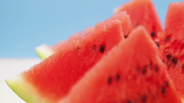 Kesilmiş sulu kırmızı karpuz parçaları mavi arkaplanda daire şeklinde döner — Stok video