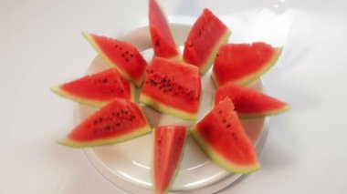 Mavi zemin üzerinde beyaz bir tabakta sulu karpuz parçaları daire şeklinde döner.