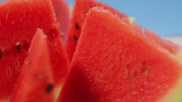 Bitar av mogen saftig röd vattenmelon på en blå bakgrund rotera i en cirkel — Stockvideo