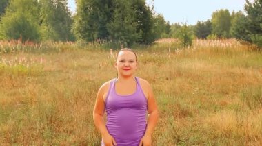 Sabahleyin çayırda genç bir kadın fiziksel egzersiz yapıyor..