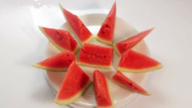 Mavi zemin üzerinde beyaz bir tabakta sulu karpuz parçaları daire şeklinde döner.