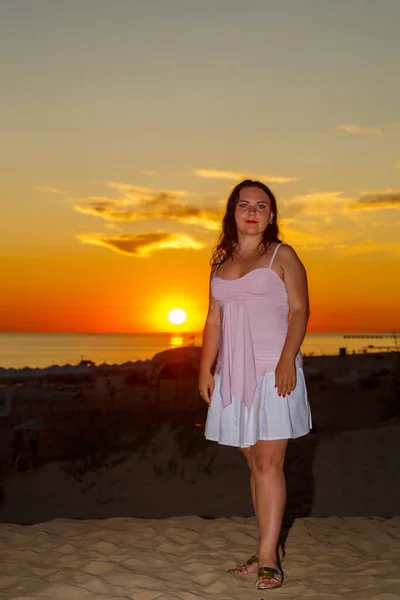 Женщина в белом платье на пляже на фоне моря на закате. — стоковое фото