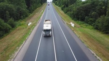 Aerovideo kamyonlar ve arabalar orman boyunca otoyol boyunca sürüyorlar.