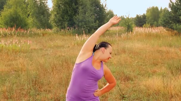 Młoda kobieta rano na łące uprawia gimnastykę. — Wideo stockowe