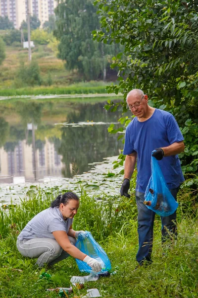 Bir erkek ve bir kadın doğadaki bir çöplüğü temizliyor..
