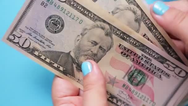 As mãos femininas contam notas de dólar cinquenta e cem em um fundo azul — Vídeo de Stock