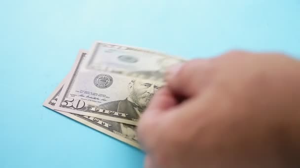 Mãos masculinas contar notas de dólar cinquenta e cem em um fundo azul — Vídeo de Stock