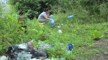 Bir adam ve bir kadın parkta gönüllü olarak izinsiz çöplüklerden plastik atıkları topluyor.